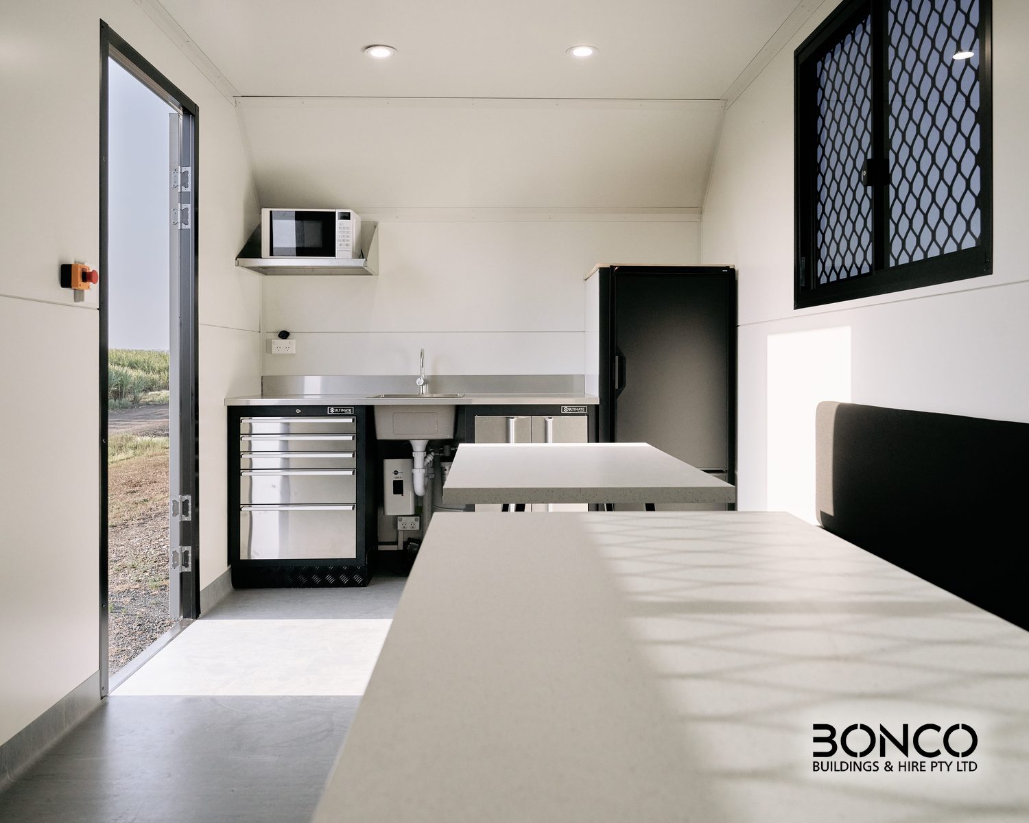Bonco mobile crib room hire – interior with lunch tables, bench seating and stainless-steel kitchenette