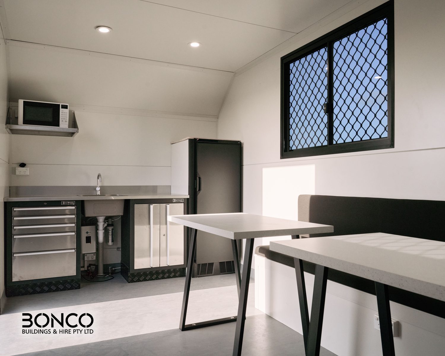 Bonco mobile crib room hire – interior with two lunch tables, kitchenette, microwave and fridge